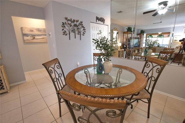 tiled dining area with ceiling fan and a textured ceiling