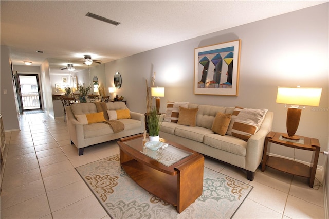 tiled living room with ceiling fan and a textured ceiling