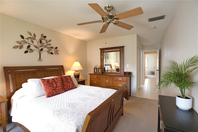 bedroom featuring ceiling fan, light carpet, and a textured ceiling