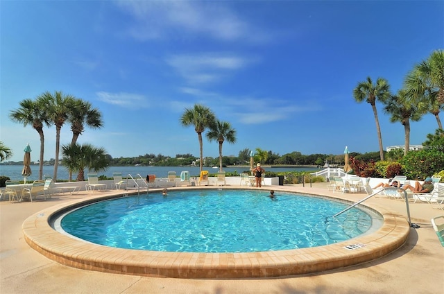 view of pool featuring a patio area and a water view