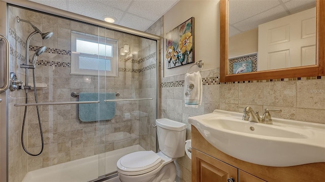 bathroom featuring vanity, toilet, a shower with shower door, and tile walls