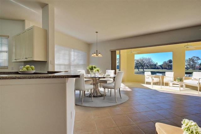 tiled dining space with ceiling fan with notable chandelier