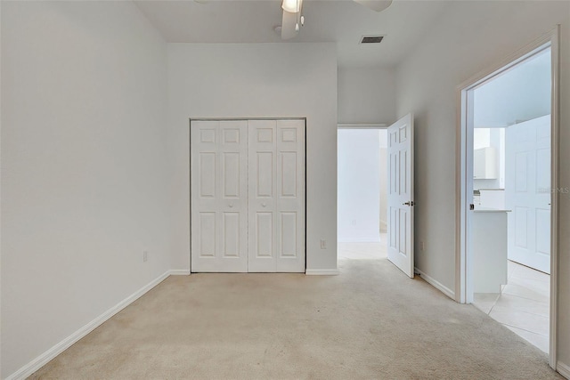 unfurnished bedroom with light carpet, a closet, and ceiling fan