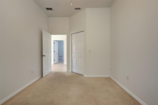 unfurnished room featuring a high ceiling and light colored carpet