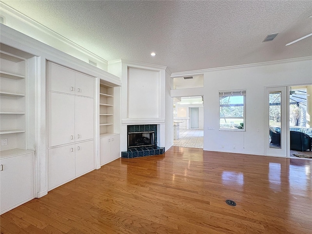 unfurnished living room with a fireplace, a textured ceiling, and light wood-type flooring