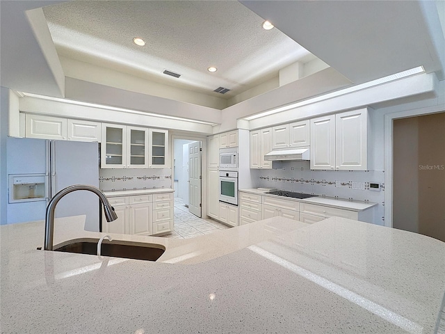 kitchen featuring sink, white appliances, white cabinetry, a textured ceiling, and decorative backsplash