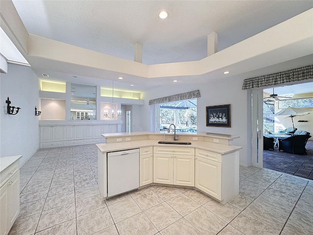 kitchen featuring sink, white dishwasher, pendant lighting, ceiling fan with notable chandelier, and white cabinets