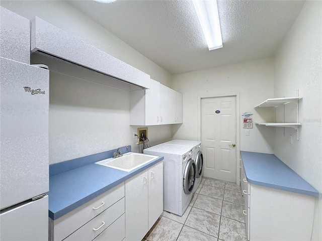 laundry room featuring sink, washing machine and dryer, cabinets, and a textured ceiling