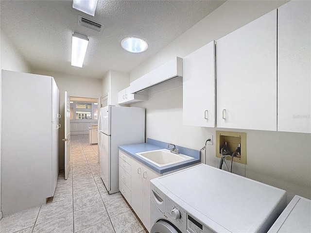 laundry area featuring washer / dryer, sink, cabinets, a textured ceiling, and light tile patterned floors