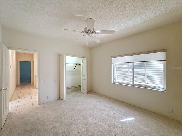 unfurnished bedroom with ceiling fan, a closet, light carpet, and a textured ceiling