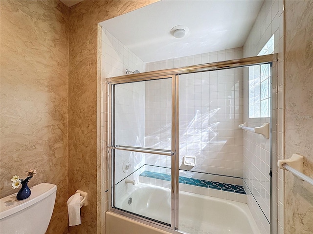 bathroom with shower / bath combination with glass door and toilet