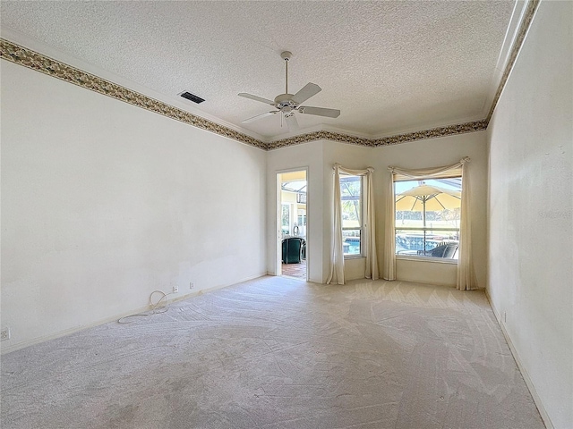 spare room with ornamental molding, light colored carpet, ceiling fan, and a textured ceiling