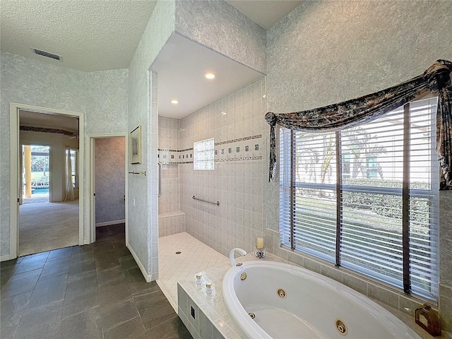 bathroom featuring a textured ceiling and separate shower and tub