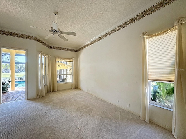 carpeted empty room with ceiling fan, lofted ceiling, ornamental molding, and a textured ceiling