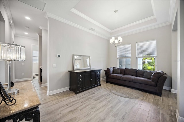 living room with crown molding, a tray ceiling, and an inviting chandelier