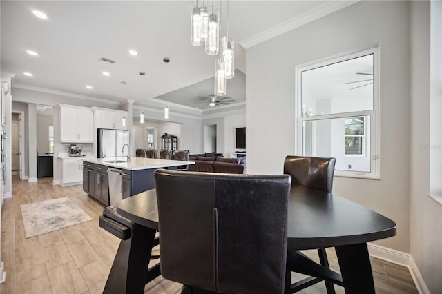 dining room with crown molding, sink, ceiling fan, and light hardwood / wood-style flooring