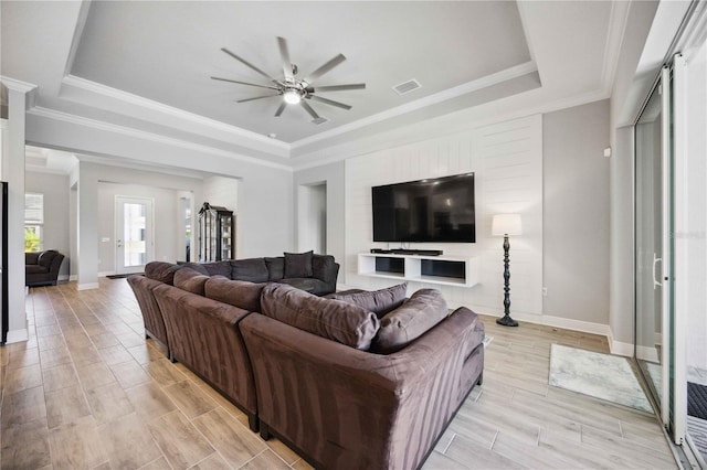 living room featuring crown molding, a raised ceiling, and ceiling fan