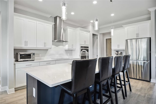 kitchen with a kitchen island with sink, white cabinetry, wall chimney exhaust hood, and appliances with stainless steel finishes