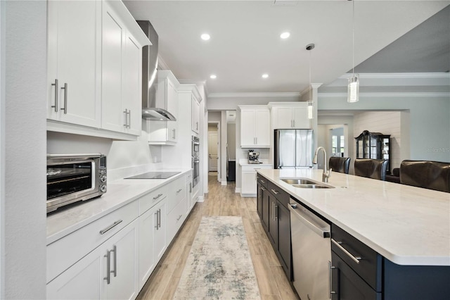 kitchen featuring sink, white cabinetry, appliances with stainless steel finishes, pendant lighting, and wall chimney range hood