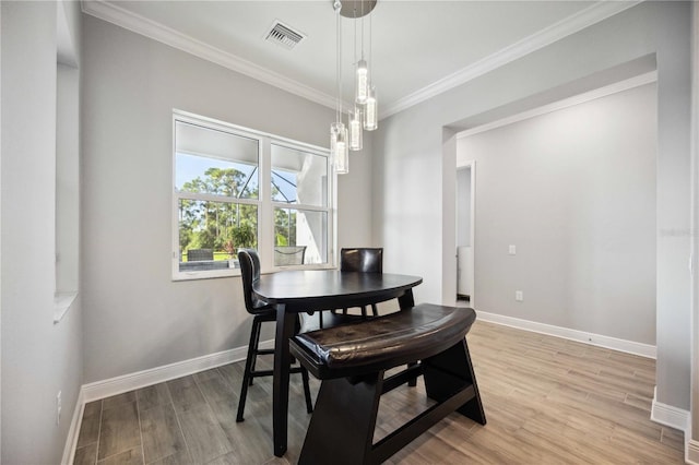 dining area featuring crown molding, light hardwood / wood-style flooring, and a notable chandelier