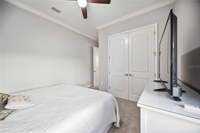 carpeted bedroom with ceiling fan, ornamental molding, and a closet