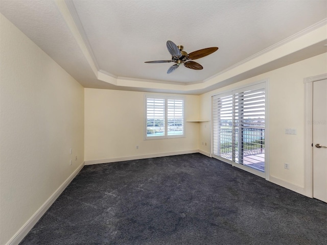 carpeted spare room with ornamental molding, ceiling fan, and a tray ceiling