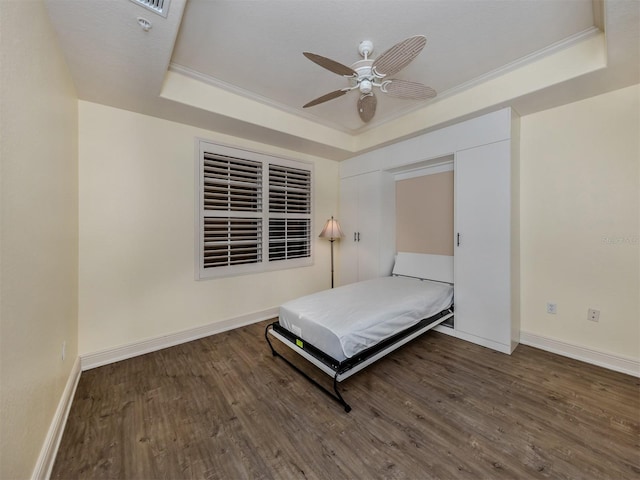 unfurnished bedroom featuring crown molding, ceiling fan, dark hardwood / wood-style flooring, and a raised ceiling