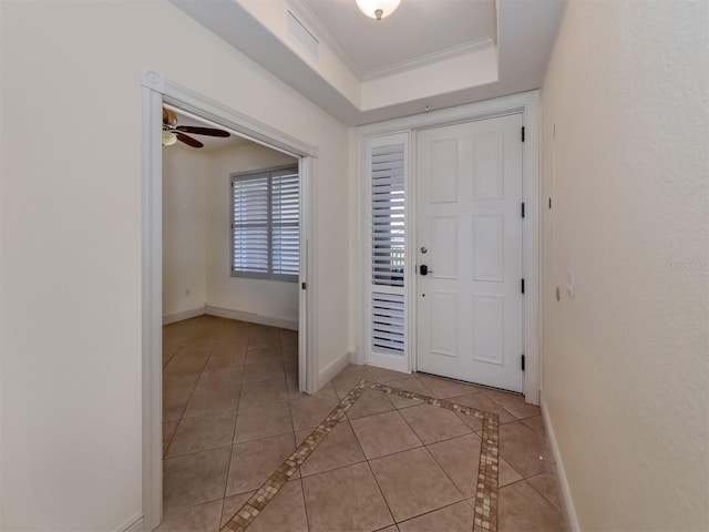 tiled entryway with crown molding, ceiling fan, and a tray ceiling