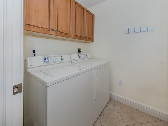 clothes washing area with cabinets, washer and dryer, and light tile patterned flooring