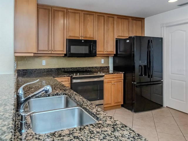 kitchen featuring sink, light tile patterned floors, black appliances, and dark stone counters