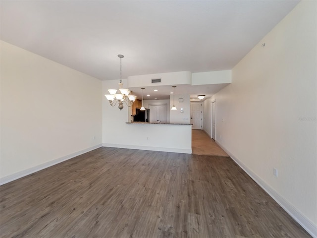 unfurnished living room featuring hardwood / wood-style flooring and a chandelier