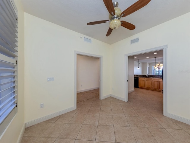 tiled spare room with sink and ceiling fan with notable chandelier