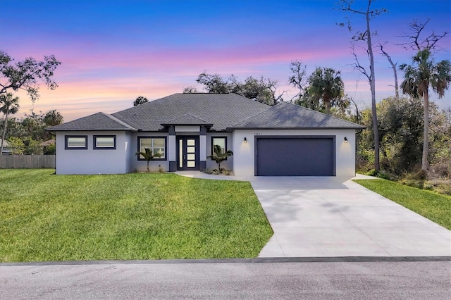 prairie-style house featuring a garage and a lawn