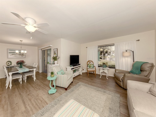 living room featuring ceiling fan with notable chandelier and light hardwood / wood-style floors