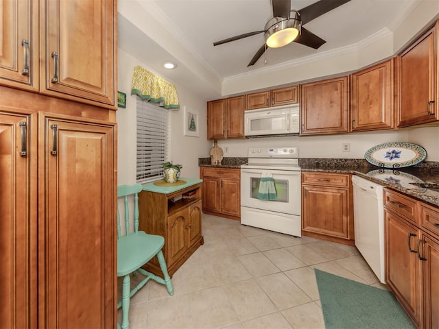 kitchen with crown molding, dark stone countertops, white appliances, and light tile patterned floors