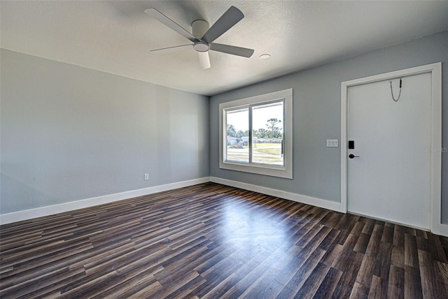 spare room with dark wood-style floors, a textured ceiling, baseboards, and a ceiling fan