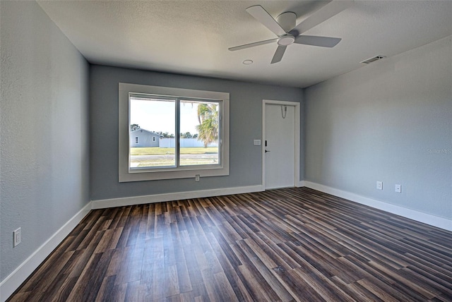 unfurnished room with a textured ceiling, dark wood finished floors, visible vents, and baseboards