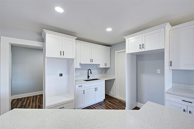 kitchen with white cabinetry, dark hardwood / wood-style floors, light stone countertops, and sink