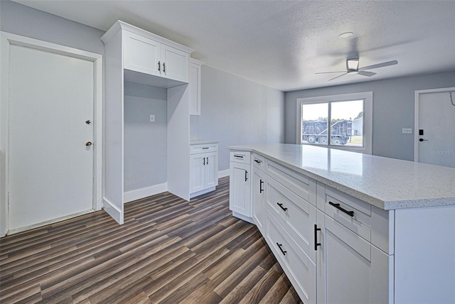 kitchen with dark hardwood / wood-style floors, white cabinetry, ceiling fan, light stone counters, and a textured ceiling