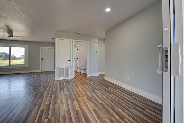 interior space with dark wood-style flooring, visible vents, a ceiling fan, a textured ceiling, and baseboards