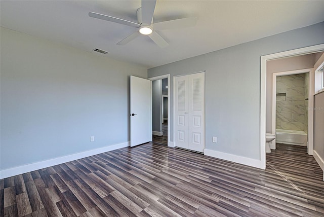 unfurnished bedroom with ceiling fan, ensuite bathroom, dark hardwood / wood-style flooring, and a closet