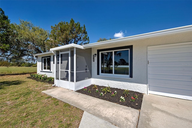 view of exterior entry with a yard, an attached garage, and stucco siding