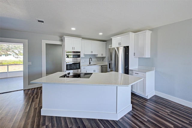 kitchen with stainless steel appliances, dark wood-style flooring, white cabinetry, and a sink