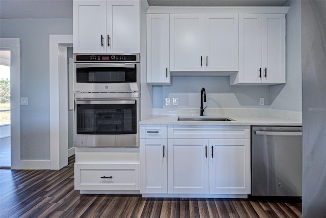 kitchen with dark wood-style floors, appliances with stainless steel finishes, a sink, and white cabinetry