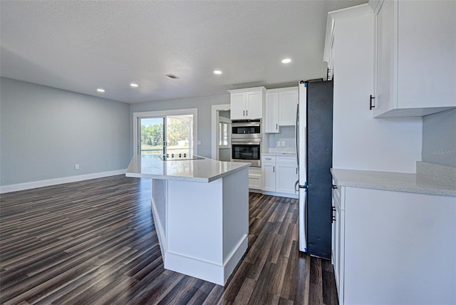 kitchen with dark wood-style flooring, visible vents, baseboards, white cabinets, and appliances with stainless steel finishes