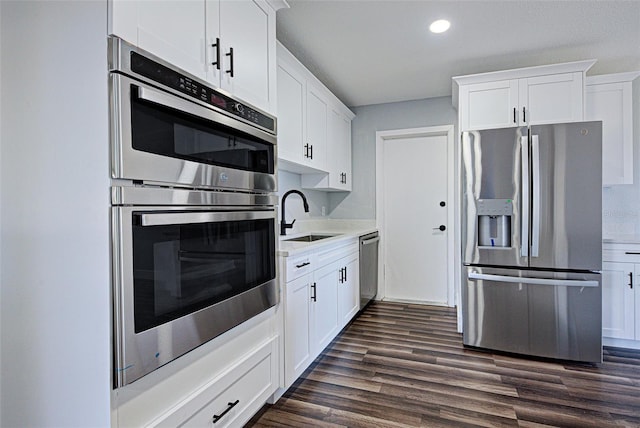 kitchen with white cabinets, dark wood-style floors, stainless steel appliances, and a sink