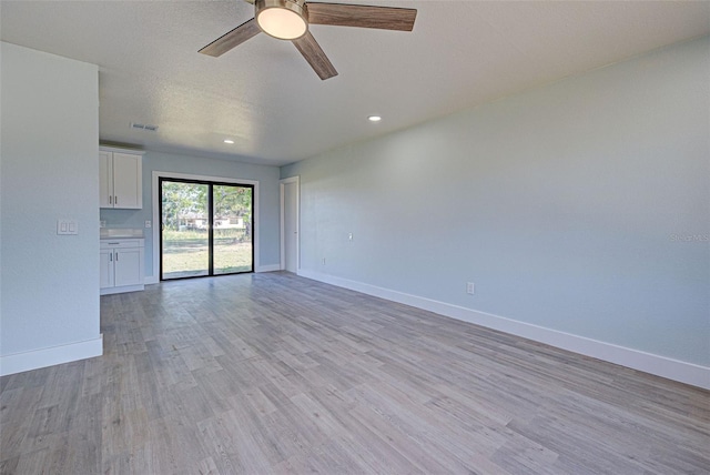 unfurnished room with a textured ceiling, ceiling fan, and light wood-type flooring