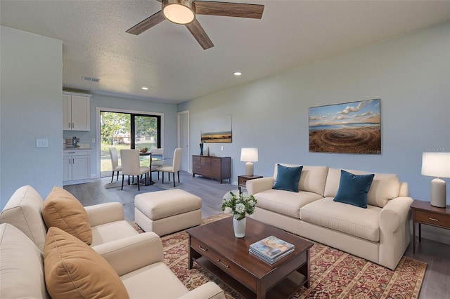 living room featuring ceiling fan and a textured ceiling