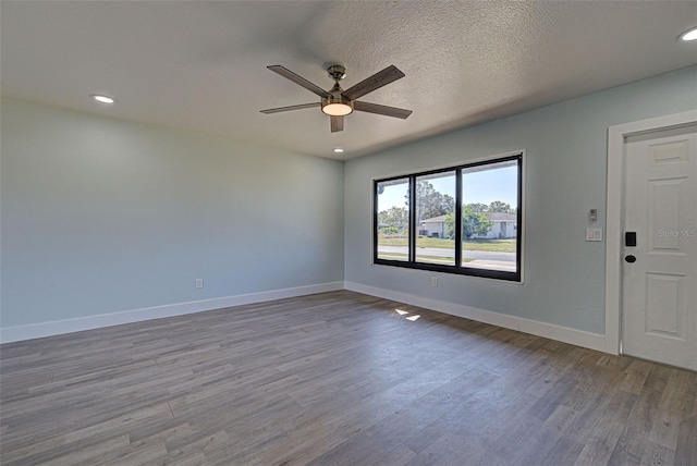 unfurnished room featuring recessed lighting, ceiling fan, a textured ceiling, wood finished floors, and baseboards