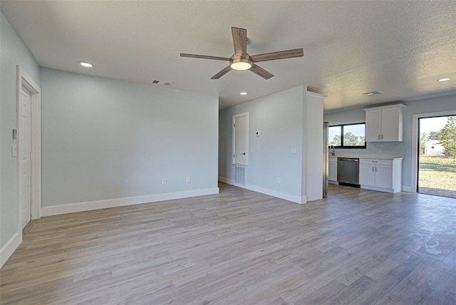 unfurnished living room featuring ceiling fan, light hardwood / wood-style flooring, and a textured ceiling